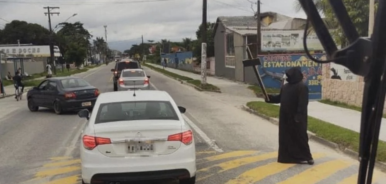 Vestido de morte, homem recepciona turistas no Litoral de SP