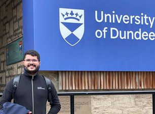 Dener Silva Miranda em frente ao logotipo da Universidade de Dundee, na Escócia, onde ele estudou pelo programa Ciência Sem Fronteiras
